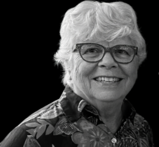 Black and white headshot of woman with white hair and glasses